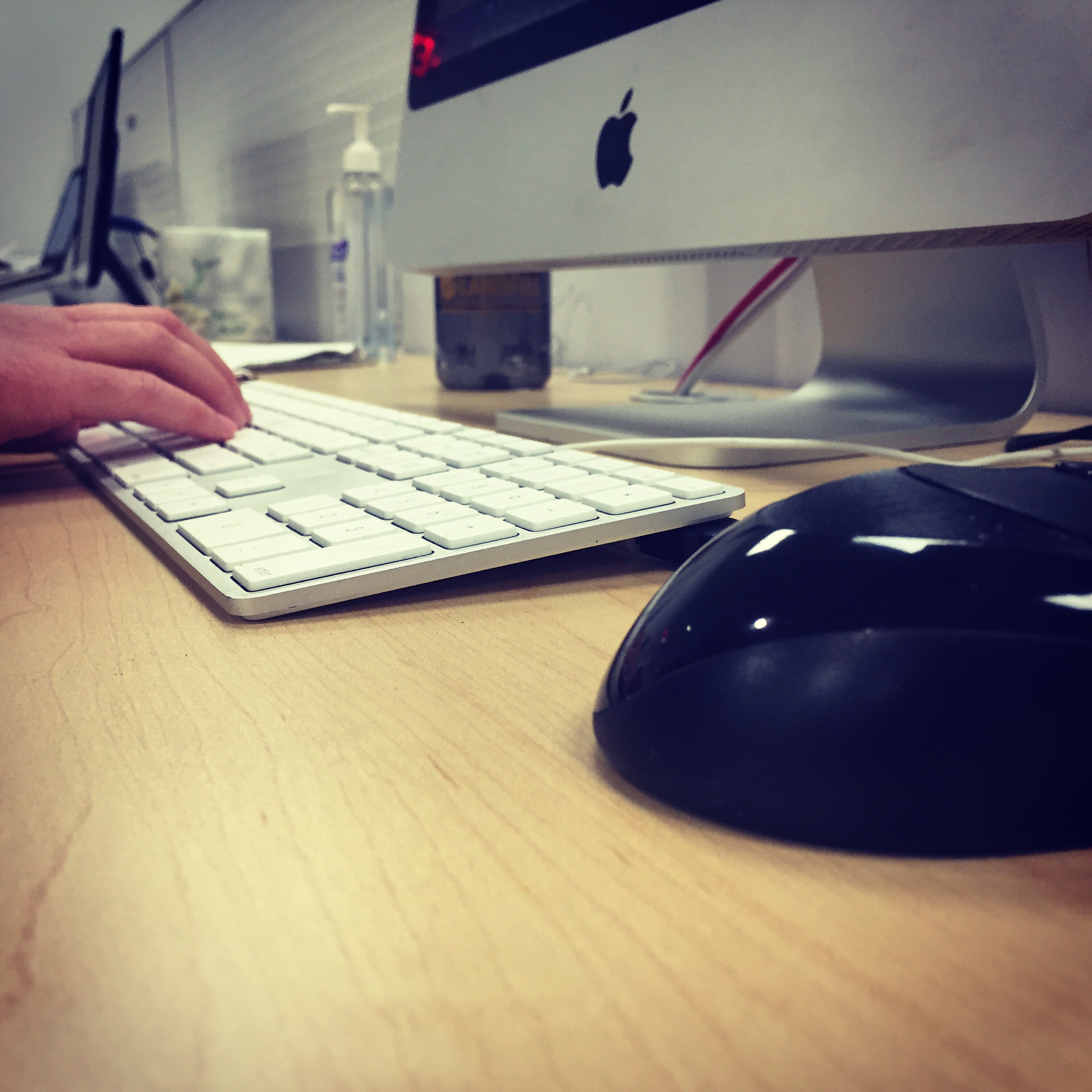 A computer user types on a keyboard in front of a computer monitor