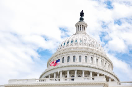 Capitol dome against a blue sky with american flag in front